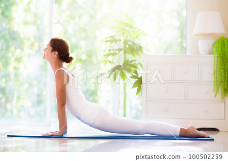 Yoga exercise at home. Fit woman stretching on mat Yoga exercise at home. Fit woman stretching on mat 100502259