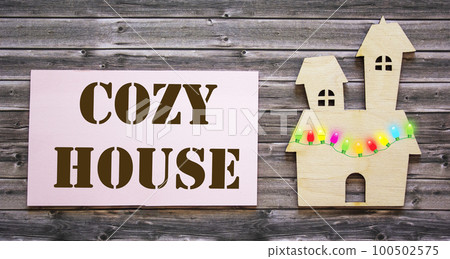 Cozy house text on a white background and wooden background. Home concept 100502575
