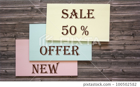 Stickers with the words 50 sale, offer, new, on a wooden table. 100502582