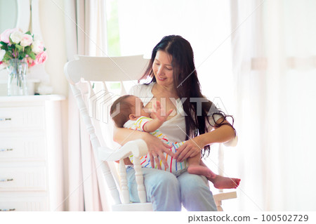 Mother nursing baby at home. Breastfeeding infant. 100502729