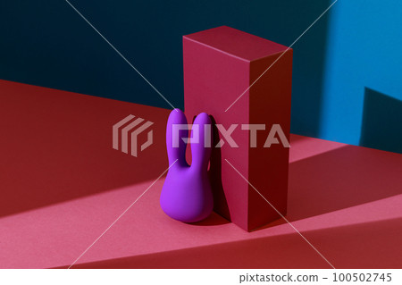Violet dildo vibrator for clitoris with pink gift box on colored background. Sex toy for adult 100502745