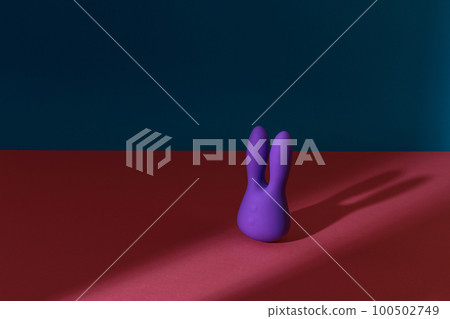 Violet dildo vibrator for clitoris on colored background with contrast shadows. Sex toy for adult 100502749