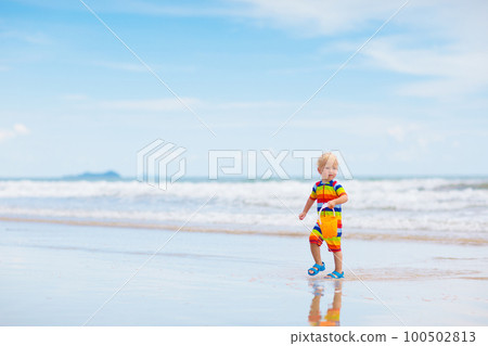 Kids play on tropical beach. Sand and water toy. 100502813