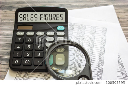 Sales figures - text on calculator next to documents and magnifying glass Sales figures - text on calculator next to documents and magnifying glass 100503595