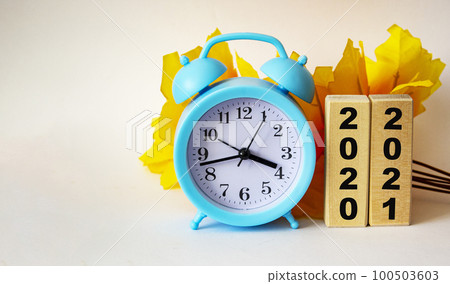 Business concepts - the inscriptions 2020 and 2021 are written on wooden blocks, an alarm clock  100503603