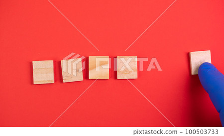 Hand in blue gloves point on clean wooden blocks on colored red background. Medical scientific or biological theme. Template for text or concept. Advertising mock up. Presentation flat lay mock up Hand in blue gloves point on clean wooden blocks on colored red background. Medical scientific or biological theme. Template for text or concept. Advertising mock up. Presentation flat lay mock up 100503733