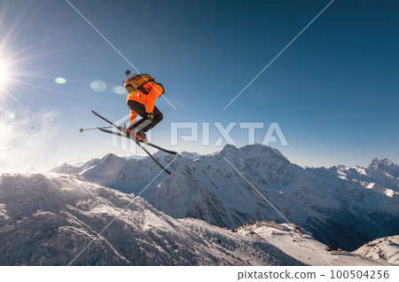 winter vacation at the ski resort. skier quickly fly in the air doing a stunt heli-skiing on the background of snow-capped mountains 100504256