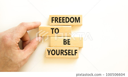 Freedom to be yourself symbol. Concept words Freedom to be yourself on wooden blocks on a beautiful white background. Businessman hand. Business, psychological freedom to be yourself concept. 100506604