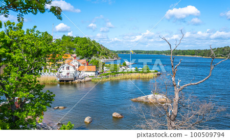 Sunny day in a small village bay on Vaxholm Island. On the coast is the Hembygdsgard Museum and a tranquil terrace with seating areas for guests. Stockholm Archipelago, Sweden Sunny day in a small village bay on Vaxholm Island. On the coast is the Hembygdsgard Museum and a tranquil terrace with seating areas for guests. Stockholm Archipelago, Sweden 100509794