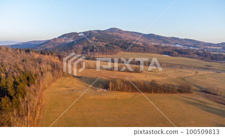 A winter landscape without snow. A clear evening during sunset over the hills of the Lusatian Mountains, Czech Republic. Aerial drone view. 100509813