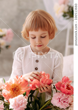 Girl 6-7 years old in a white dress holds a flower Girl 6-7 years old in a white dress holds a flower 100513660