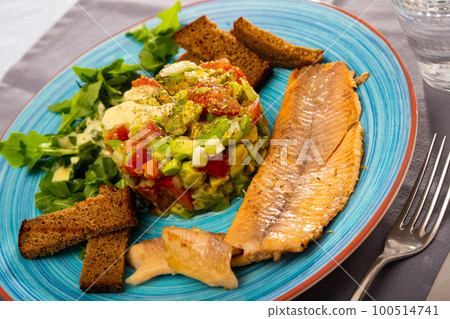 Salad guacamole with fresh tomatoes and arugula served with trout fillet Salad guacamole with fresh tomatoes and arugula served with trout fillet 100514741