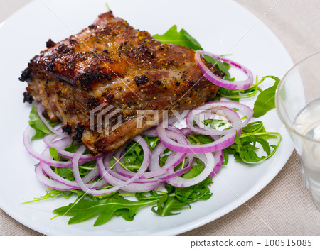 Baked under sauce tasty pork ribs at plate with arugula and onion 100515085