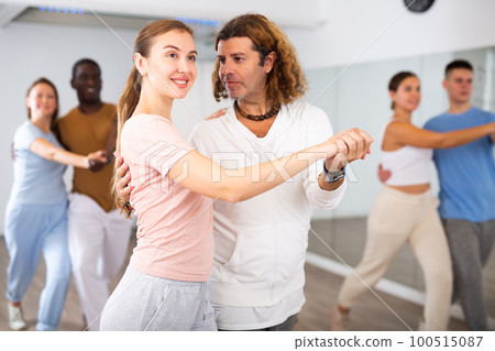 Group of diverse happy adult people dancing modern social dances in pairs at fitness studio 100515087