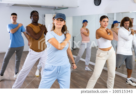 Women and men dancing synchronous group choreography in dance hall 100515343