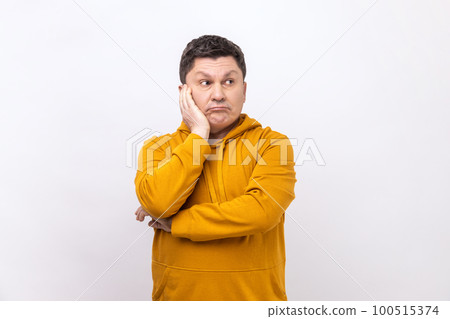 Doubtful middle aged man contemplating leaning head on hand, pondering difficult question, trying to make right choice, wearing urban style hoodie. Indoor studio shot isolated on white background. 100515374