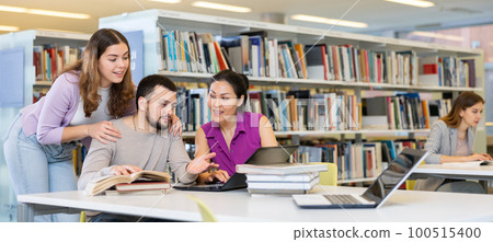 Cheerful students studying in library with books and laptop Cheerful students studying in library with books and laptop 100515400