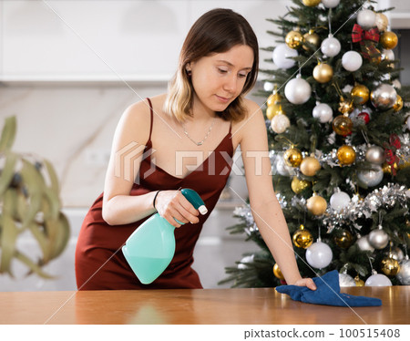Young woman wipes the table with a damp cloth 100515408