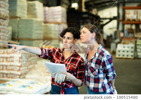 Two women verifying check list in warehouse 100515480