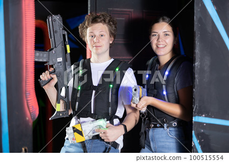 Boy and girl posing with lasertag guns in arena Boy and girl posing with lasertag guns in arena 100515554
