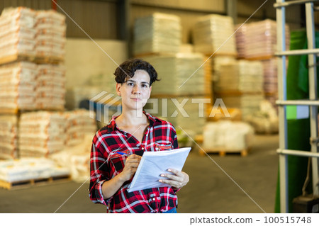 Cheerful woman checking documentation in warehouse 100515748