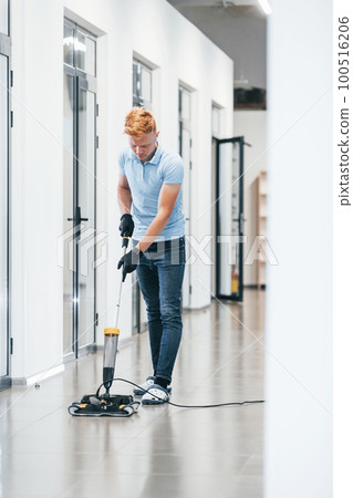 Young man works in the modern office. Uses vacuum cleaner 100516206