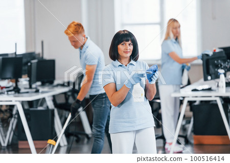 Group of workers clean modern office together at daytime Group of workers clean modern office together at daytime 100516414