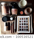 makeup and cosmetics on top of a wooden table next to an ipad, coffee mug, lip balknots, eyeliner 100516521