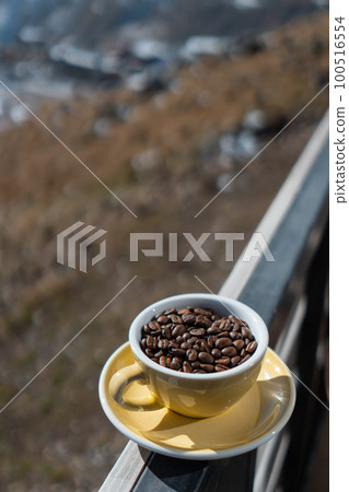 cup with brown coffee beans on mountain background cup with brown coffee beans on mountain background 100516554