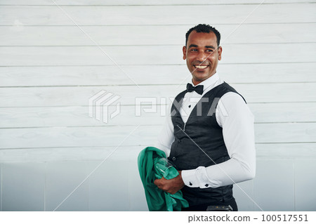 Black waiter in formal clothes is at his work outdoors at sunny daytime 100517551