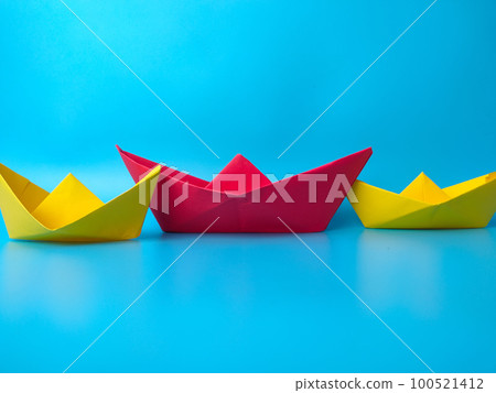 Leadership concept. Red leader paper ship leading among others on blue background Leadership concept. Red leader paper ship leading among others on blue background 100521412