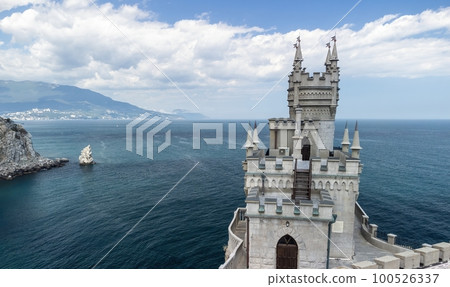 Crimea Swallow's Nest Castle on the rock over the Black Sea. It is a tourist attraction of Crimea. Amazing aerial view of the Crimea coast with the castle above abyss on sunny day. Crimea Swallow's Nest Castle on the rock over the Black Sea. It is a tourist attraction of Crimea. Amazing aerial view of the Crimea coast with the castle above abyss on sunny day. 100526337