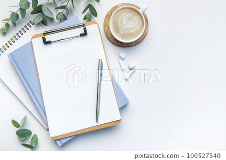 Modern white office desk table with coffee, notebook and other supplies. 100527540