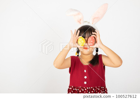Happy Easter Day. Smile Asian little girl wearing easter bunny ears holding colorfull eggs closes eyes with testicles isolated on white background with copy space, Happy child in holiday 100527612