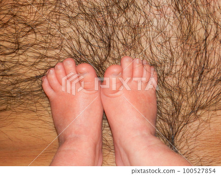 Newborn baby's feet on a hairy male chest close-up. Baby's legs on the father's breast. Soft focus 100527854