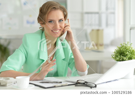 Young businesswoman talking on phone at work 100529186