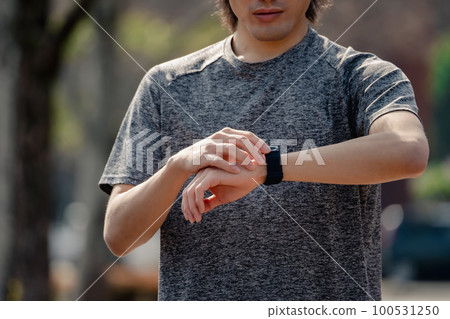 A man jogging checking his smartwatch A man jogging checking his smartwatch 100531250