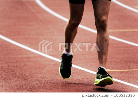 Runner running on athletics track 100532380