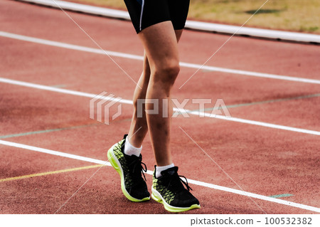 Runner running on athletics track 100532382