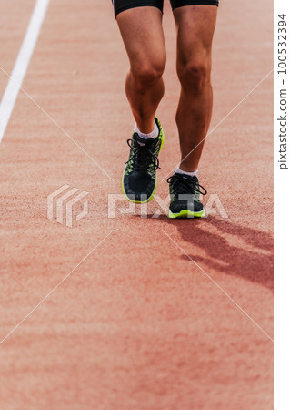 Male runner running straight on athletics track 100532394