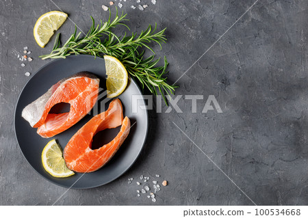 Steak of fresh raw red fish salmon with lemon, rosemary and pepper on black background 100534668