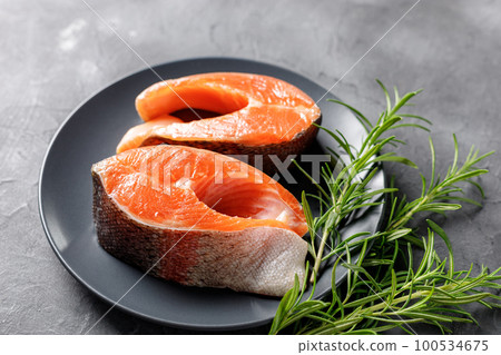 Steak of fresh raw red fish salmon with lemon, rosemary and pepper on black background 100534675