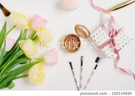 Pink and yellow tulip flowers, accessories and cosmetics. The layout of a female desktop in a home office. Flat lay, top view, blog title background. 100534690