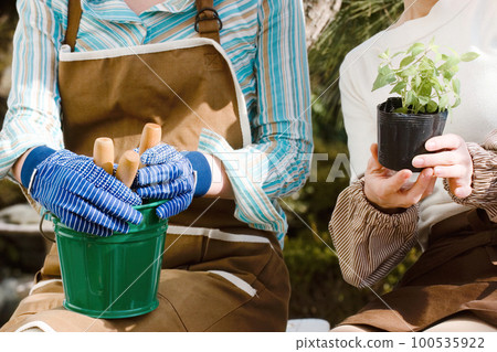 Close-up female with gardening tools sitting in the garden 100535922
