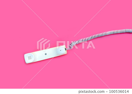 Handset of landline phone on pink background. 100536014