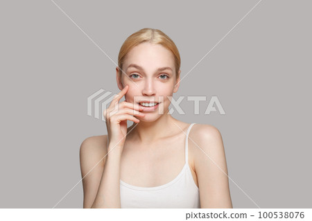 Cute blonde woman touching her face and smiling Cute blonde woman touching her face and smiling 100538076