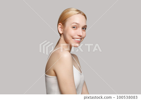 Blonde woman in white top smiling isolated on grey background. Beauty, cosmetics, skincare, glamour 100538083