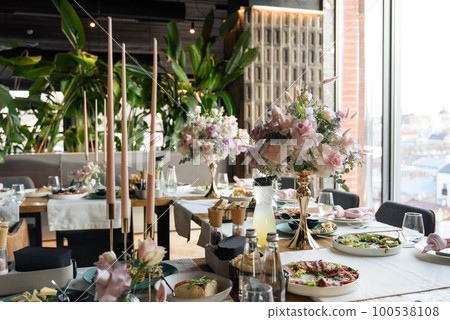 served table in the restaurant is decorated with a luxurious bouquet. Garden roses, eustoma, populus eucalyptus. pastel colours 100538108