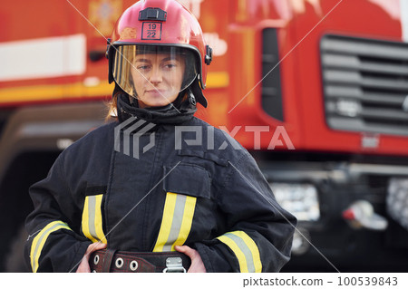 Female firefighter in protective uniform standing near truck 100539843