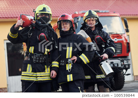 Group of firefighters in protective uniform that outdoors near truck Group of firefighters in protective uniform that outdoors near truck 100539844